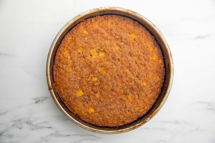 Fully-baked layer of paleo carrot cake in an 8-inch round metal cake pan.