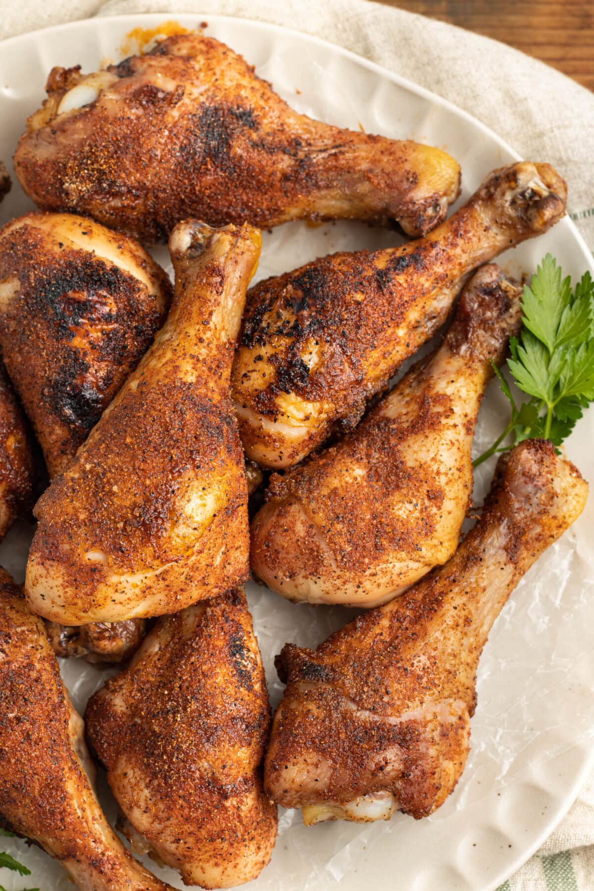 Rubbed and smoked chicken legs piled on a platter lined with parchment paper.