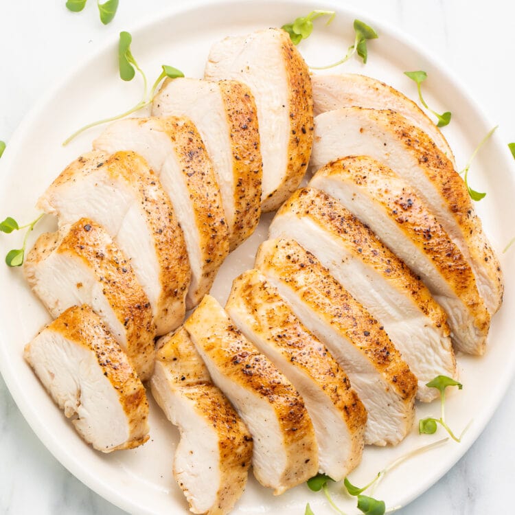 Overhead view of two sliced sous vide chicken breasts arranged on a white plate.