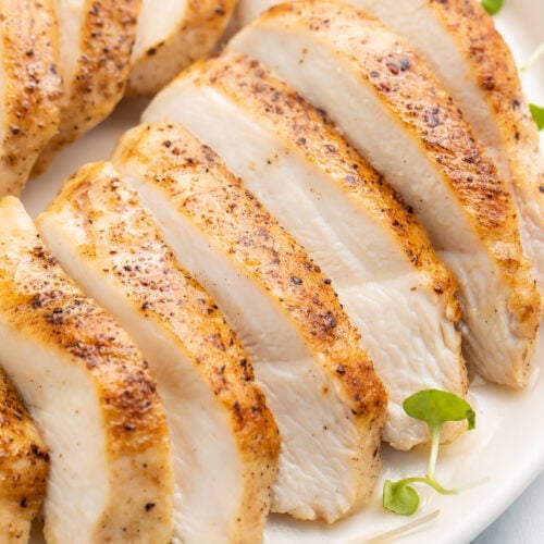 Sliced sous vide chicken breast arranged on a platter to show the juicy white meat and the seasoned skin at the same time.