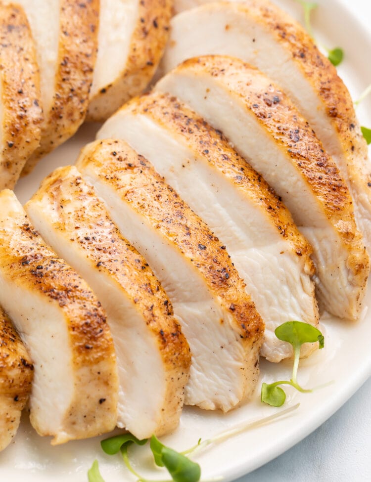 Sliced sous vide chicken breast arranged on a platter to show the juicy white meat and the seasoned skin at the same time.