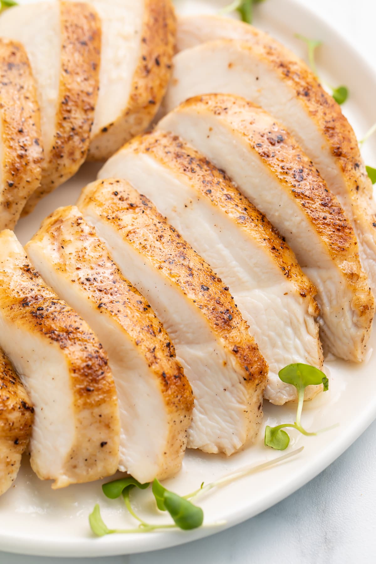Sliced sous vide chicken breast arranged on a platter to show the juicy white meat and the seasoned skin at the same time.