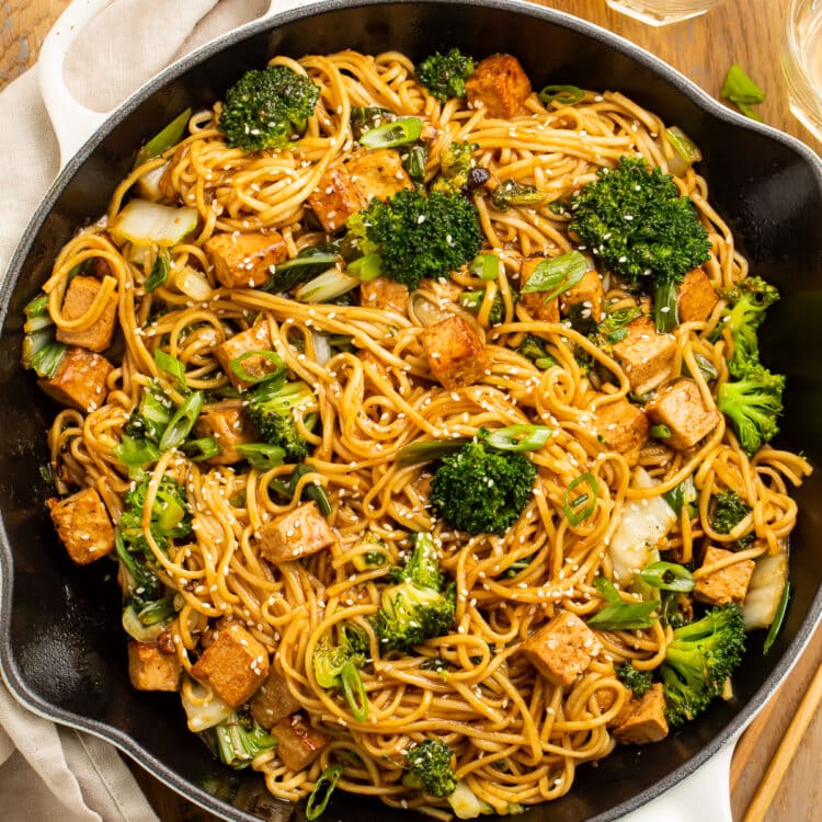 Zoomed out over head view of stir fry noodles with tofu and veggies in a large skillet.