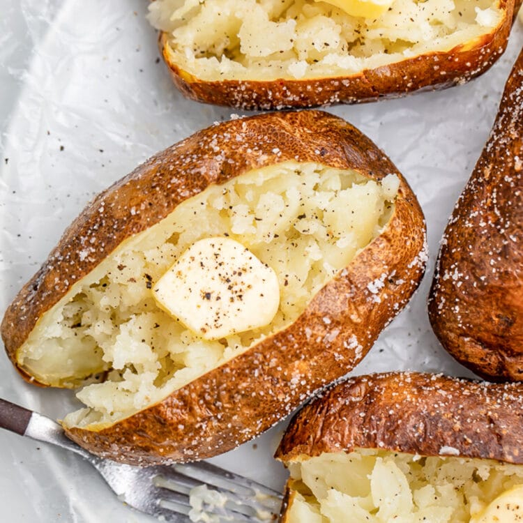 Air fryer baked potato crusted in salt, split in the middle and fluffed, then topped with butter and pepper.