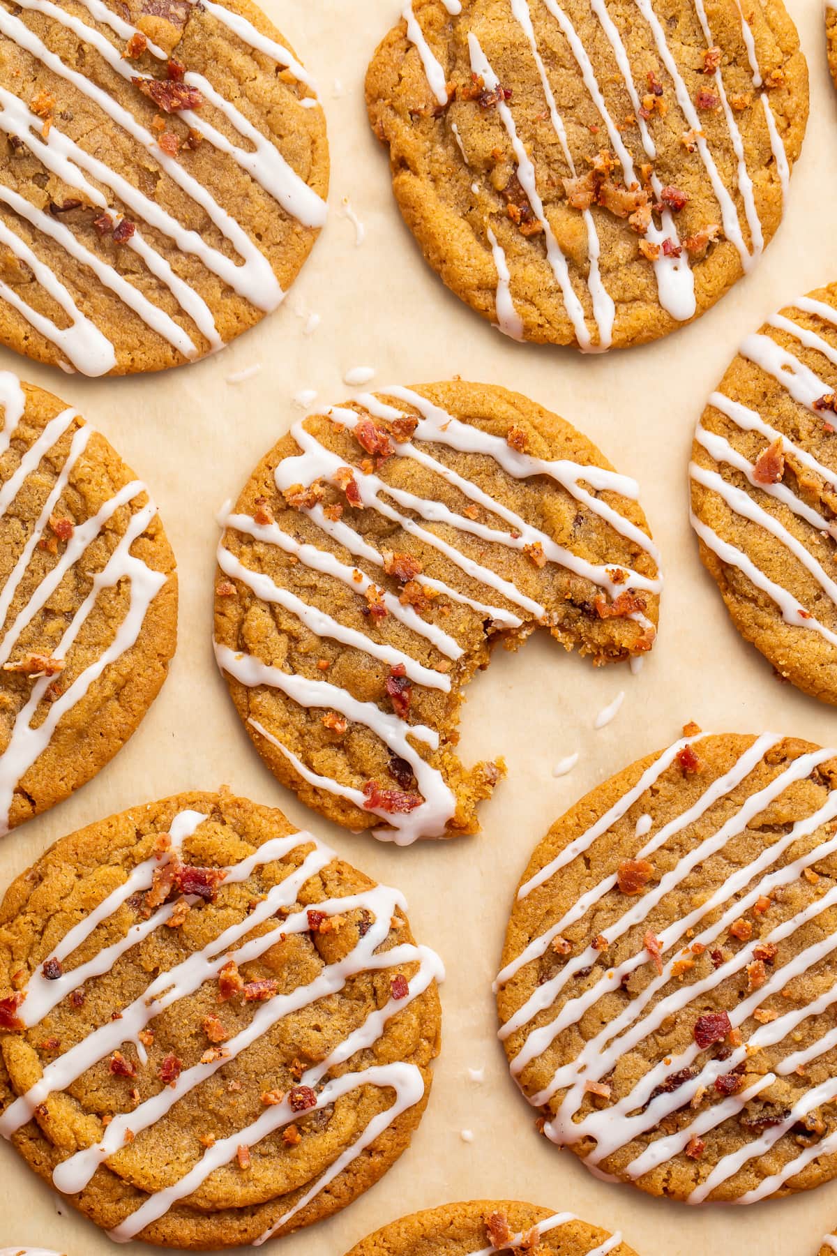 Bacon cookie butter cookies with a cinnamon glaze drizzle arranged on parchment paper.