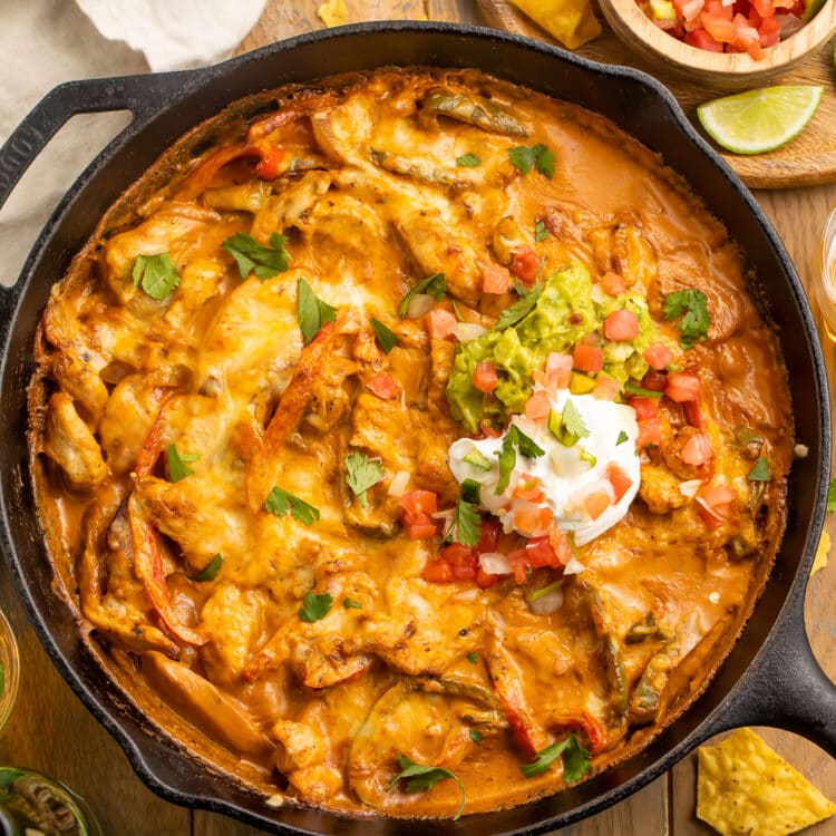 Chicken fajita casserole with a creamy sauce and a dollop of sour cream in a cast-iron skillet.