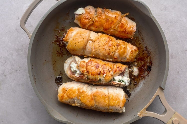 Golden brown seared chicken roulade in a large skillet.
