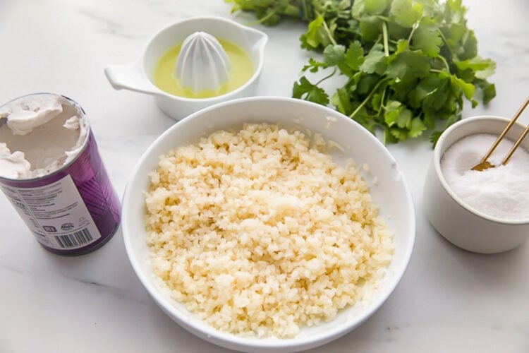 Ingredients for cilantro lime cauliflower rice in on a light marble countertop.