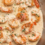 Cooked garlic shrimp in a rich cream sauce, in a large silver skillet.