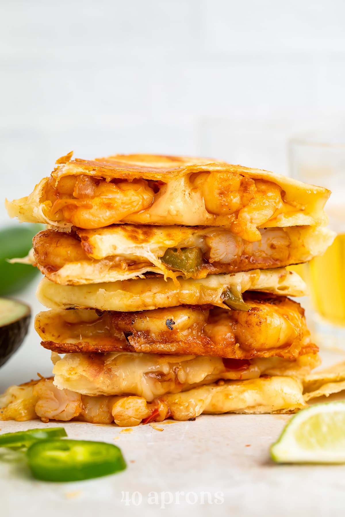 Shrimp quesadilla wedges stacked on top of eachother with cheese oozing out the sides.