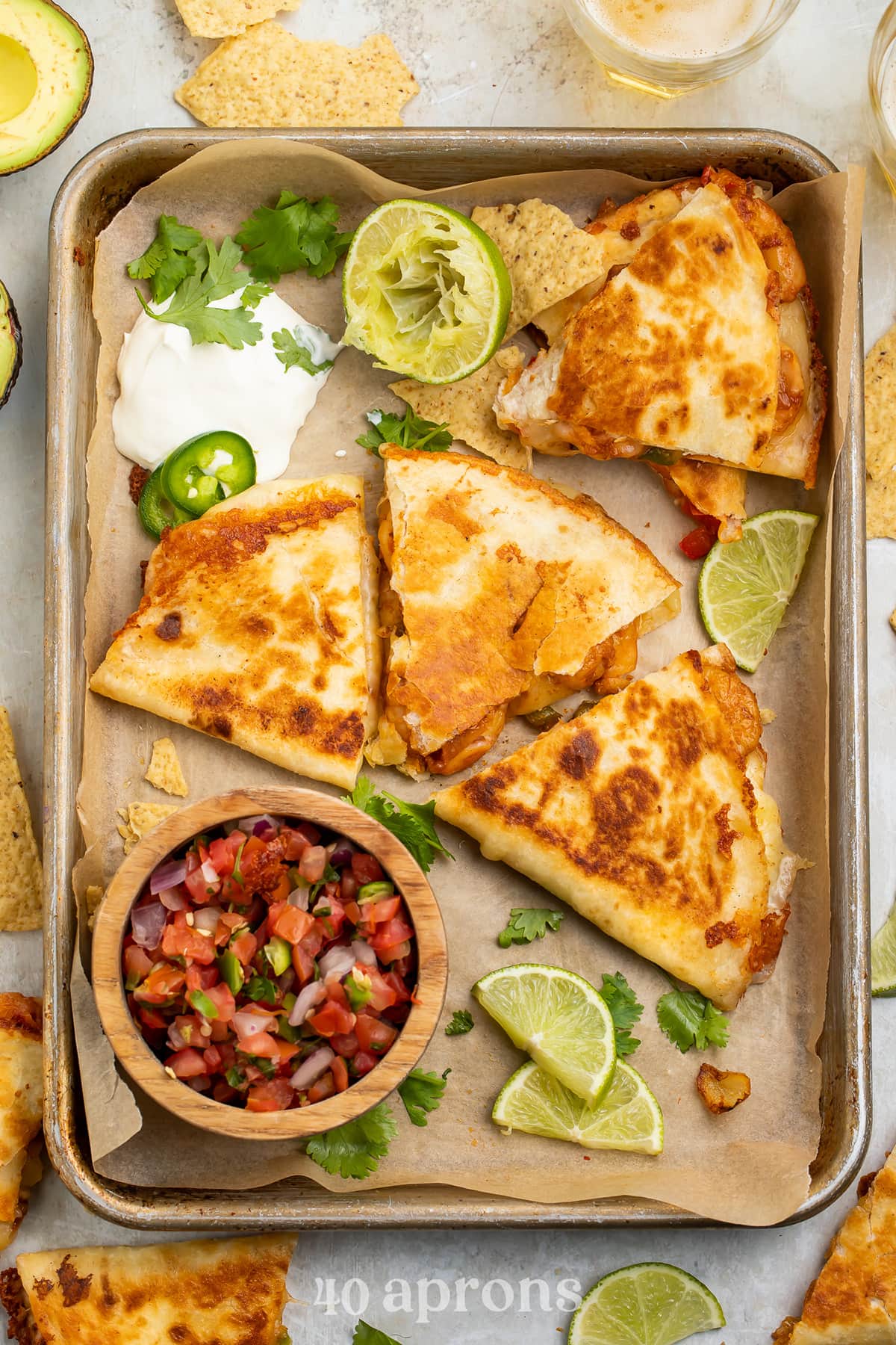 Overhead view of a shrimp quesadilla cut into 3 wedge-shaped slices surrounded by toppings.