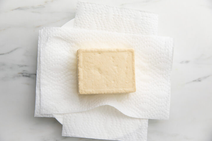 A block of tofu resting on layers of paper towels.