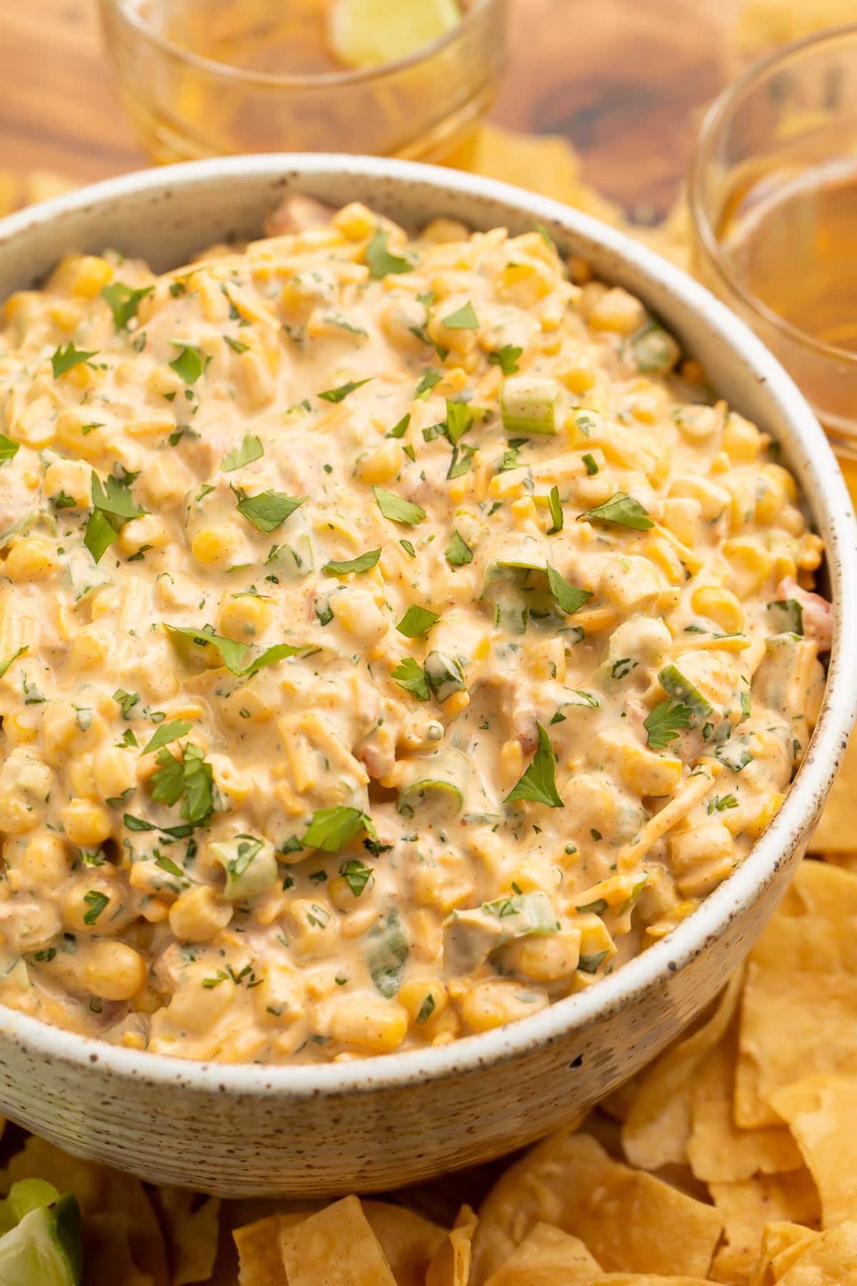 A bowl of Mexican corn dip surrounded by tortilla chips.
