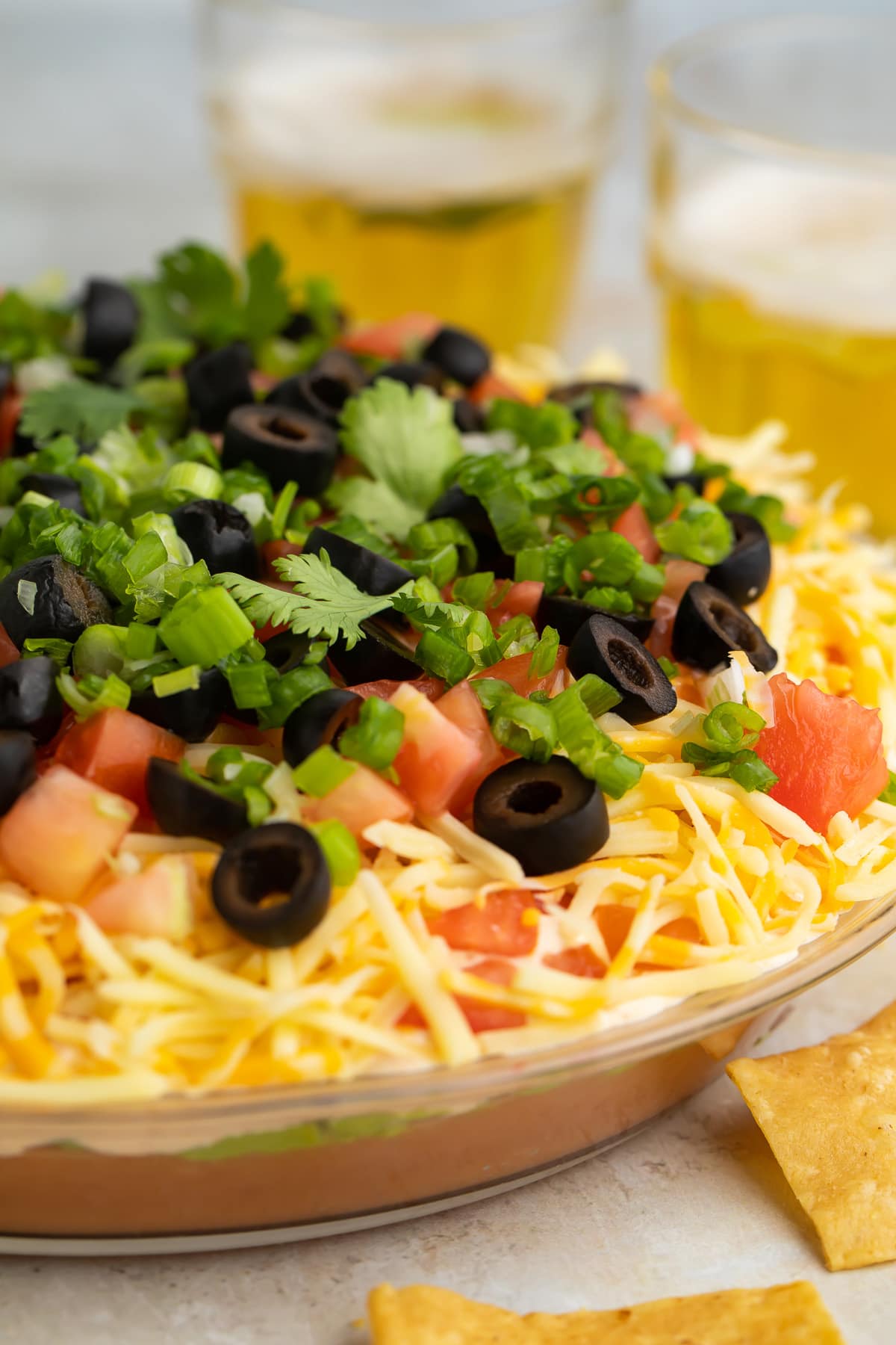 A side-view of a large glass bowl filled with a 7 layer dip.