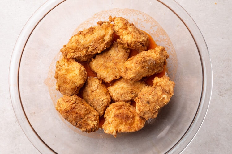Breaded, fried boneless chicken wings without buffalo sauce in a large glass mixing bowl.