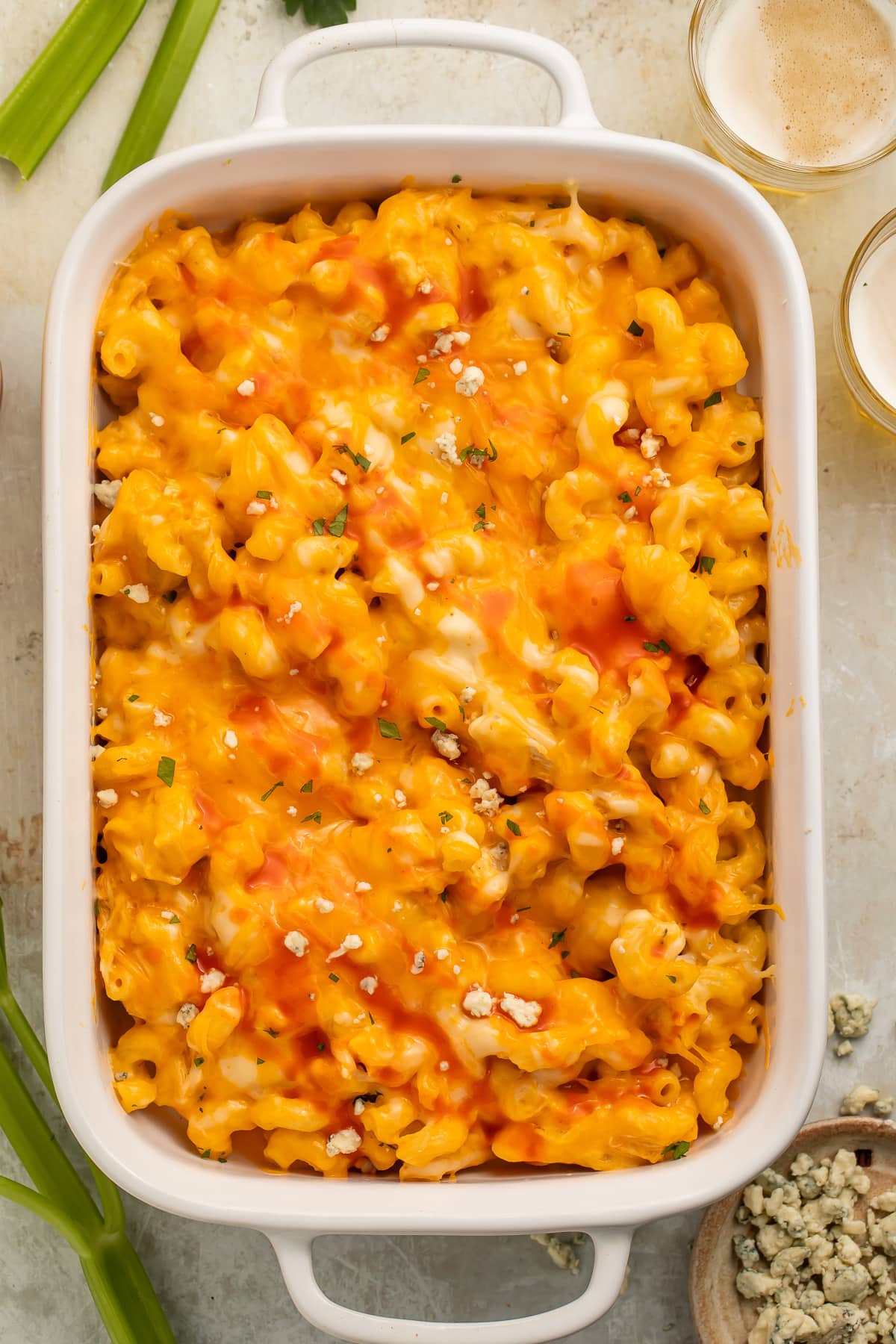 A large rectangular casserole dish filled with creamy, melty buffalo chicken mac and cheese topped with blue cheese crumbles.