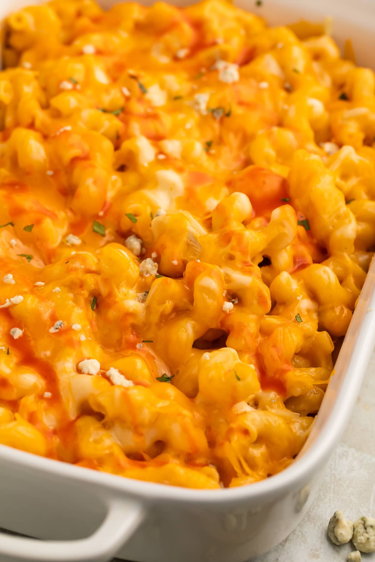 Close-up of orange buffalo chicken mac and cheese in a large rectangular casserole dish.