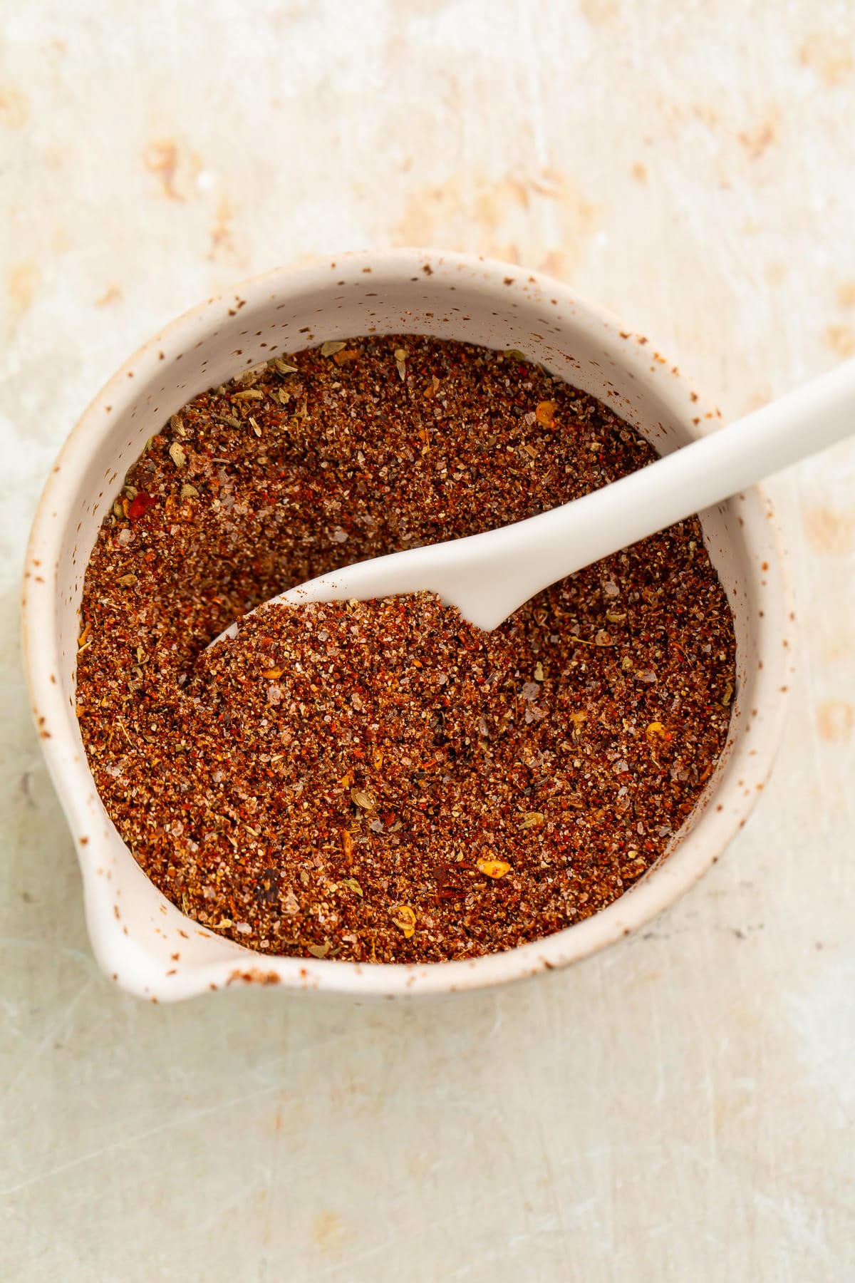 Overhead view of a small bowl filled with a rich, deep reddish-brown blend of spices for chicken taco seasoning.