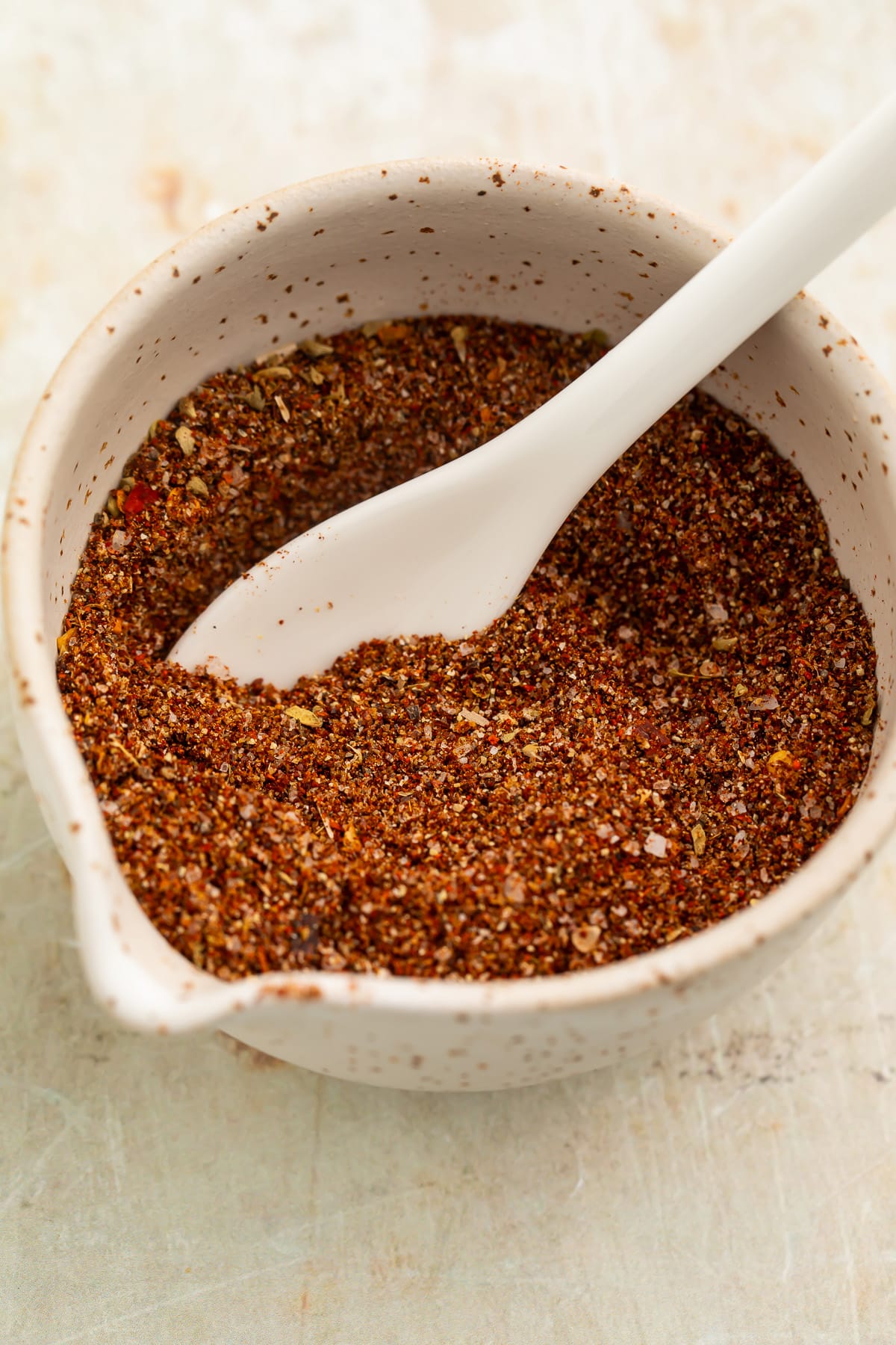 Overhead view of a small bowl filled with a rich, deep reddish-brown blend of spices for chicken taco seasoning.