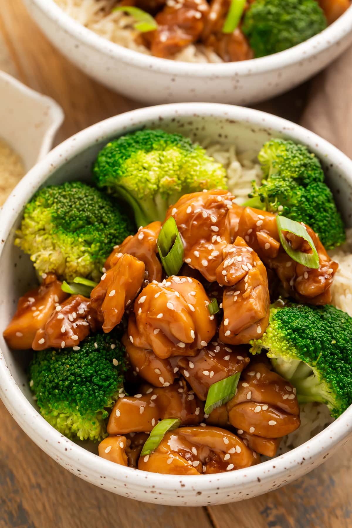 Angled side view of a bowl of Instant Pot chicken teriyaki with steamed broccoli on a bed of white rice.