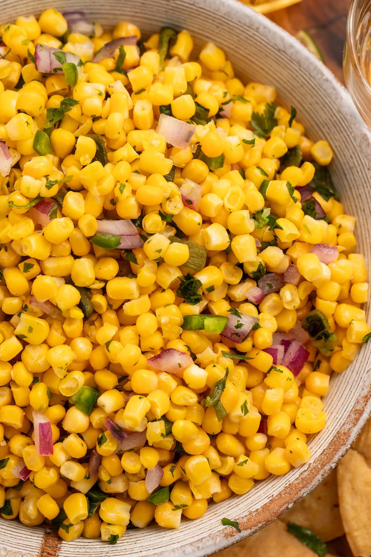 A bowl of roasted chili corn salsa surrounded by tortilla chips.