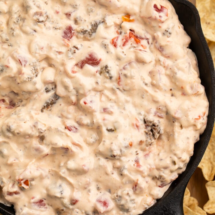 Overhead view of a cast-iron skillet filled with cream cheese sausage dip surrounded by tortilla chip scoops.