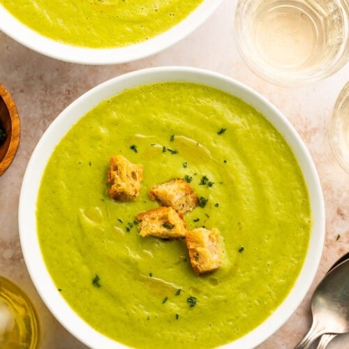 Two bowls of creamy zucchini soup on a table.
