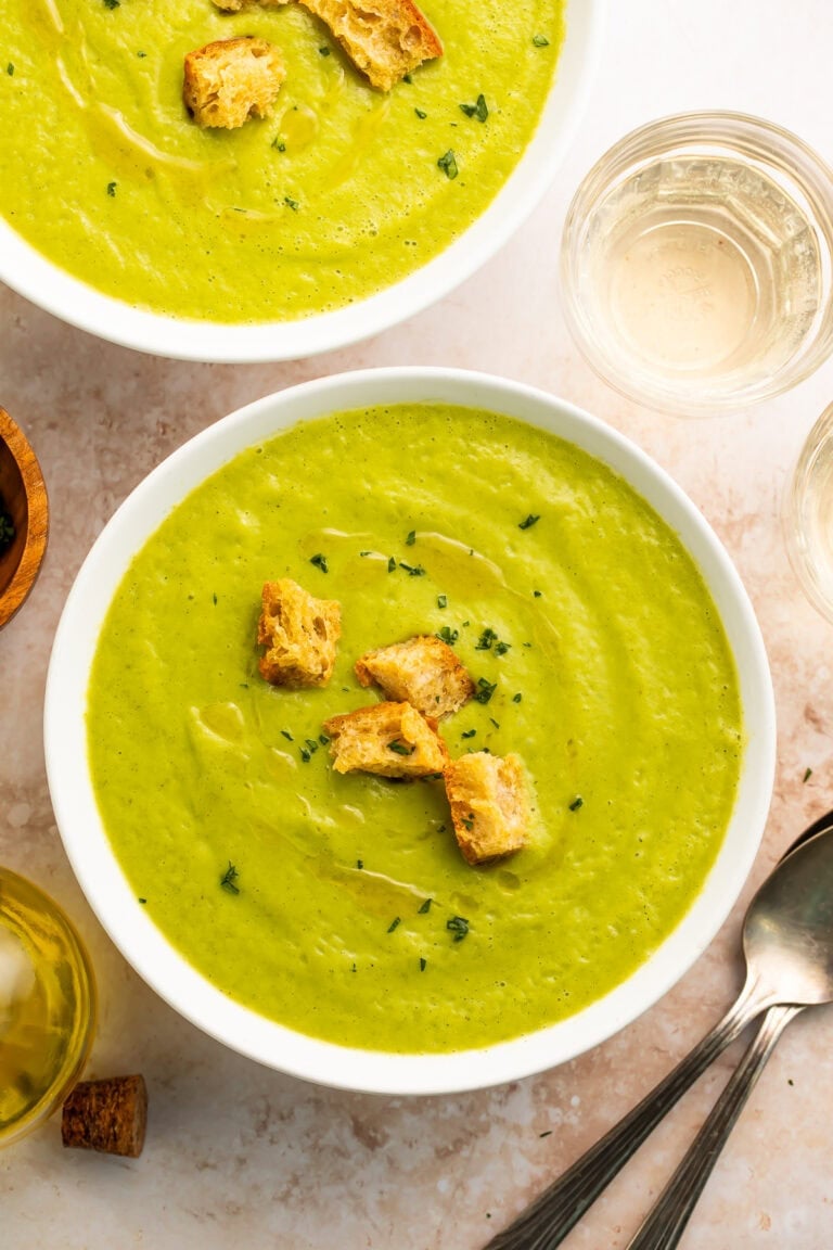 Two bowls of creamy zucchini soup on a table.