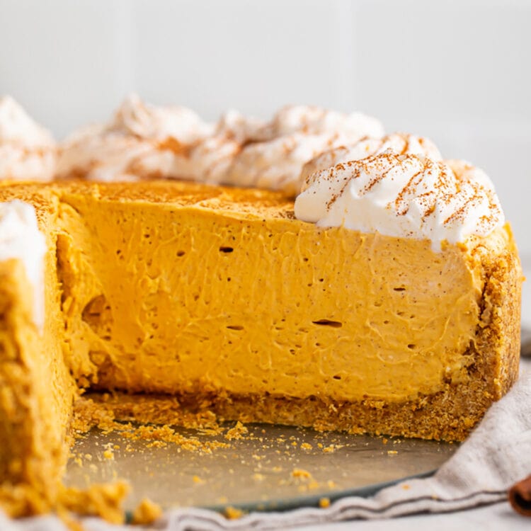 Side view of a no bake pumpkin cheesecake. One slice is missing, revealing the texture of the inside of the cheesecake.