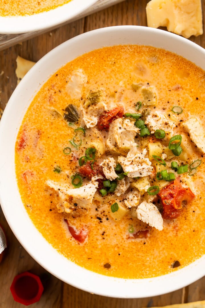 Overhead view of a bowl of Instant Pot creamy cajun chicken pasta soup on a wooden table.