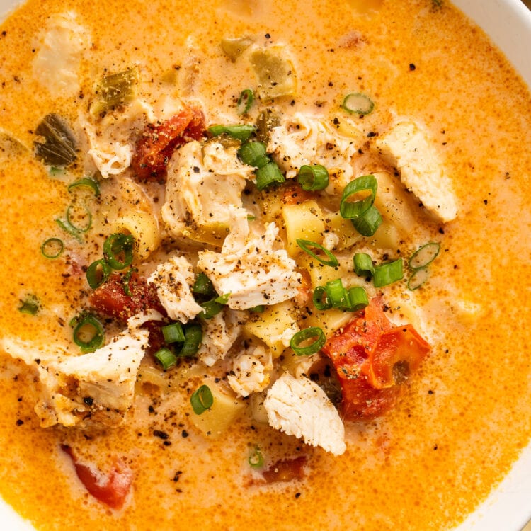 Overhead view of a bowl of Instant Pot creamy cajun chicken pasta soup on a wooden table.