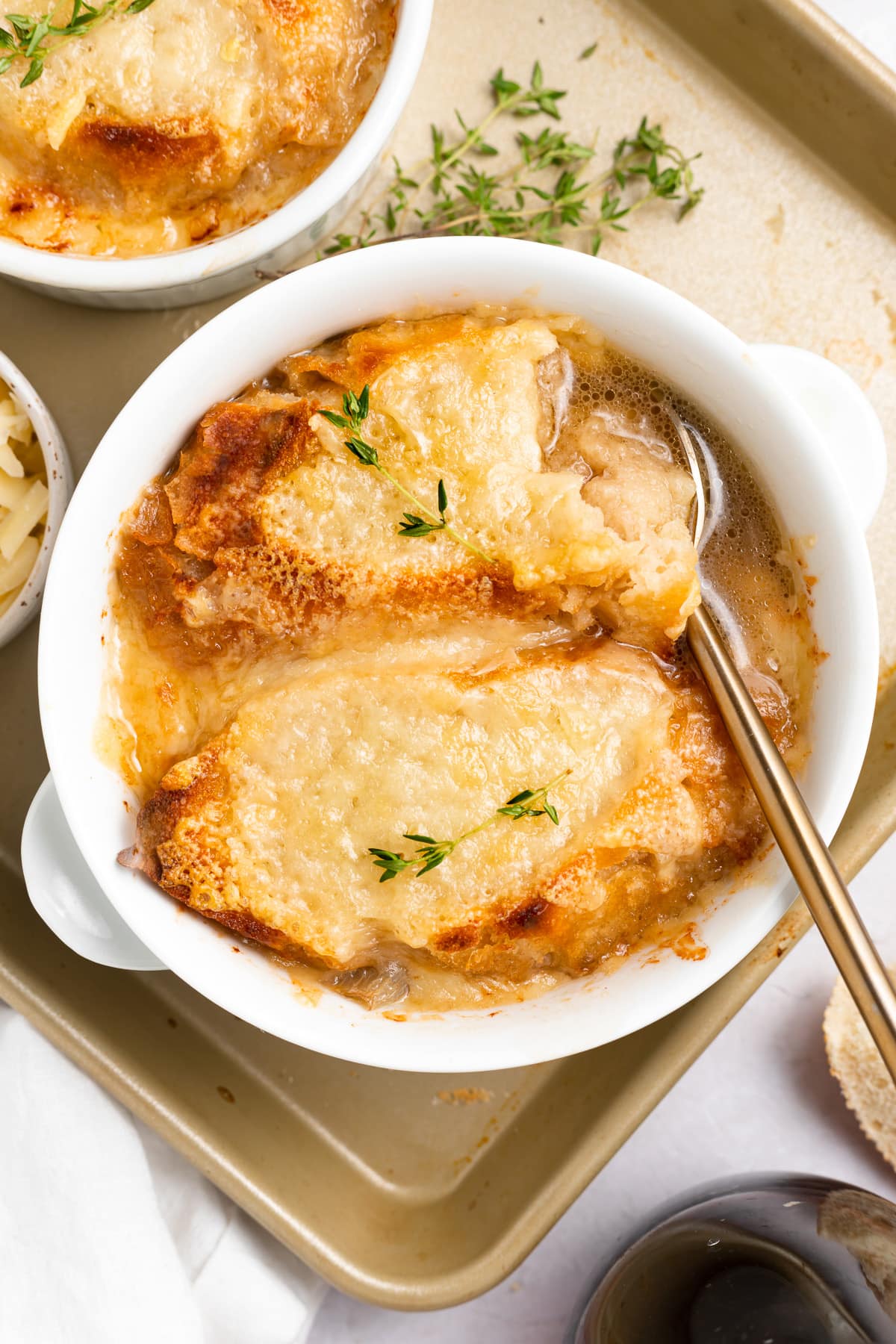 Top-down look at a large ramekin of Instant Pot French Onion soup topped with French bread and melted Gruyère cheese.