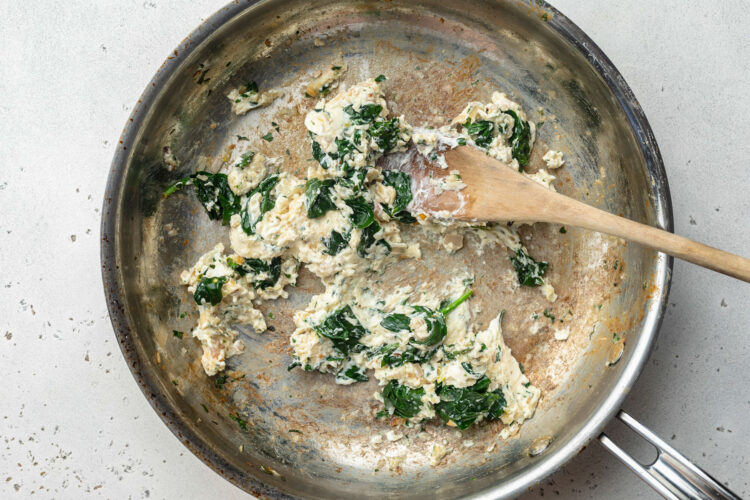 Cream cheese spinach filling for Salmon Wellington in a large skillet.