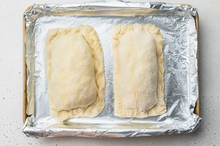 Two salmon fillets fully encased in puff pastry sheets, pinched closed around the edges.