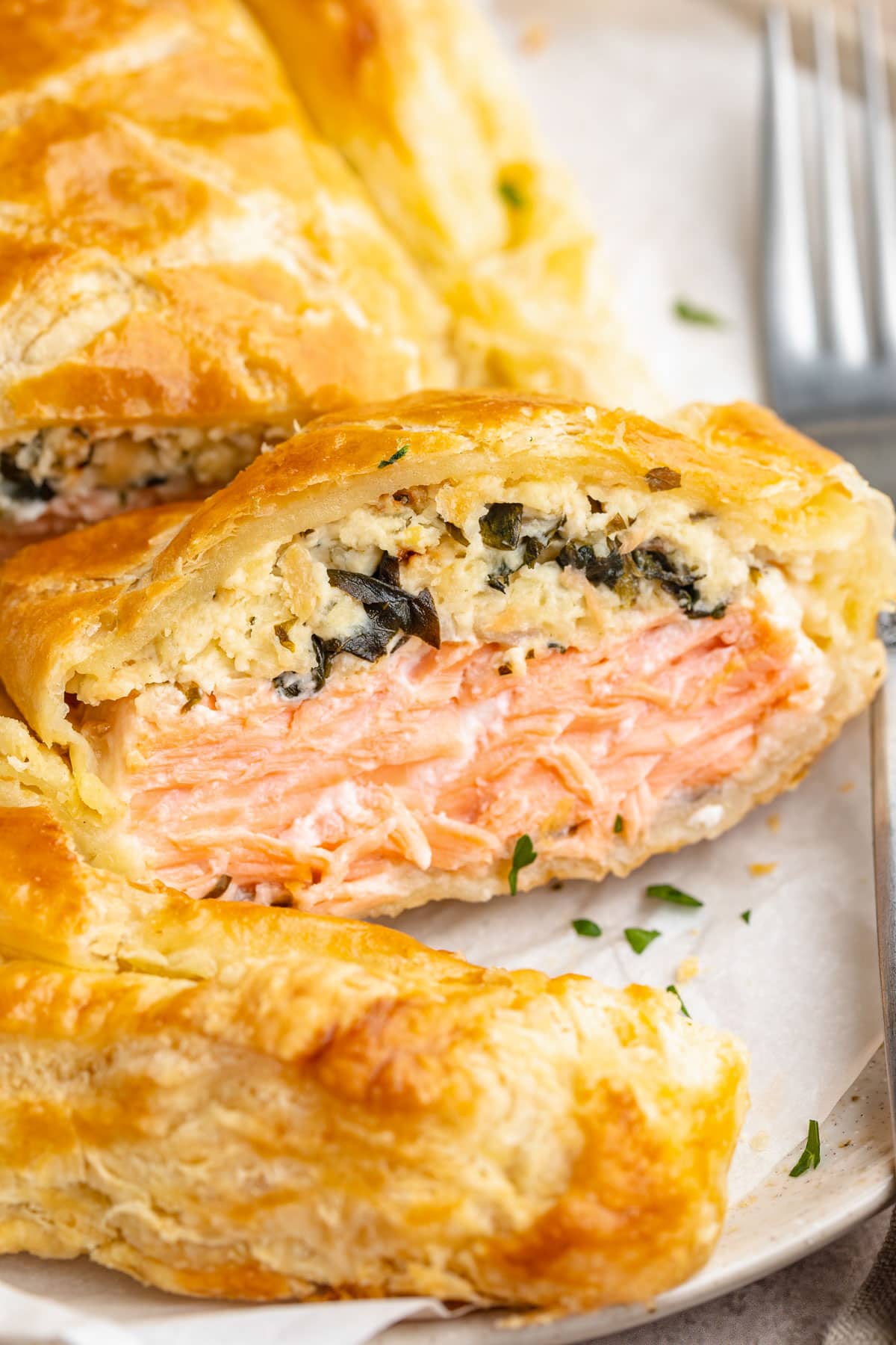 Close up of a slice of salmon wellington, positioned on its side to show the salmon filling.