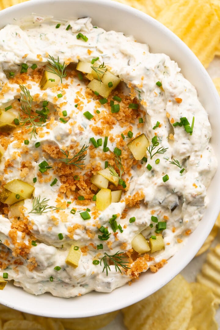 Close-up look at a large white bowl holding a fried pickle dip made with cream cheese, sour cream, dill pickles, and breadcrumbs.