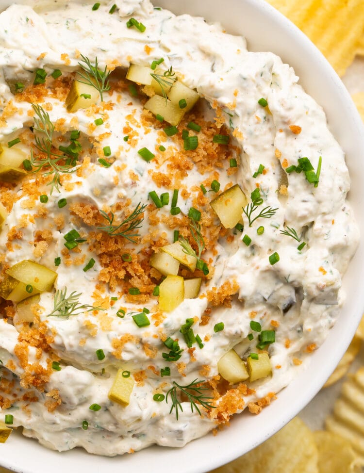 Close-up look at a large white bowl holding a fried pickle dip made with cream cheese, sour cream, dill pickles, and breadcrumbs.