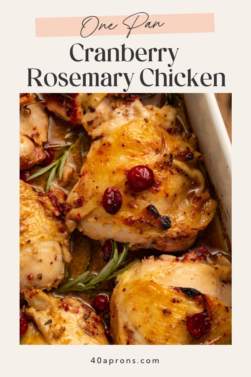 Golden-brown chicken thighs with fresh cranberries and rosemary sprigs in a white baking dish with pan sauce.
