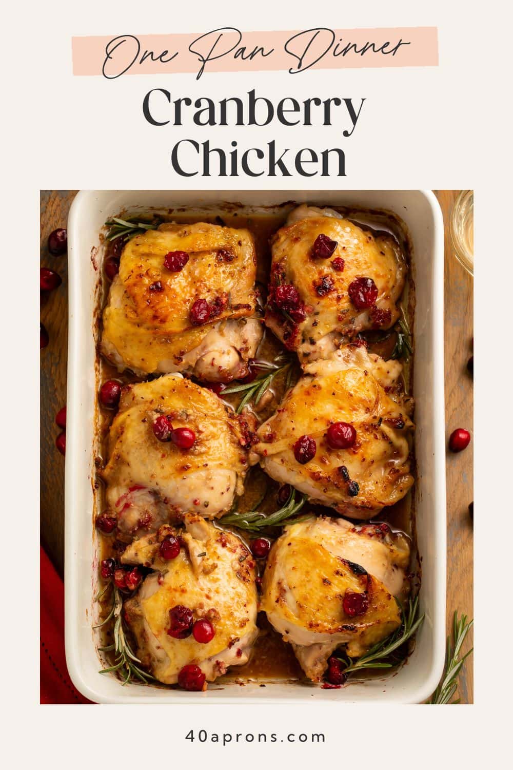One-pan cranberry chicken dinner with caramelized skin, fresh rosemary, and bright red cranberries in ceramic dish.