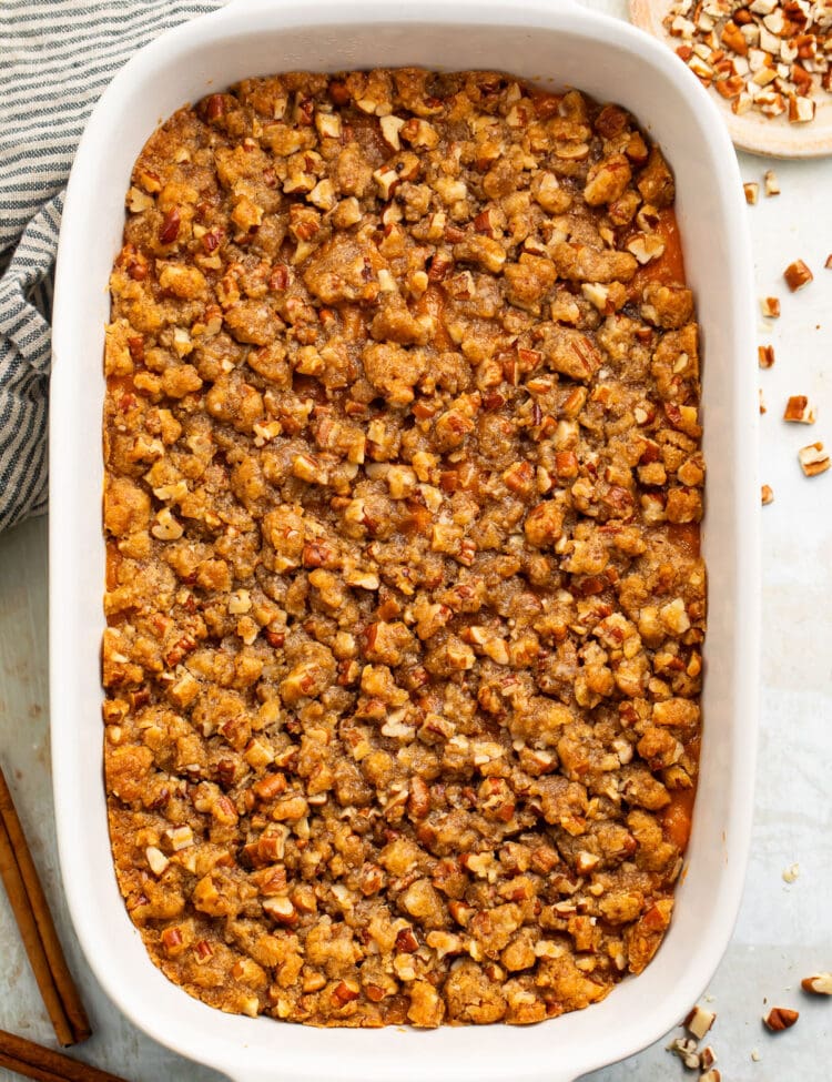 A casserole dish of Ruth's Chris sweet potato casserole topped with pecans and brown sugar.