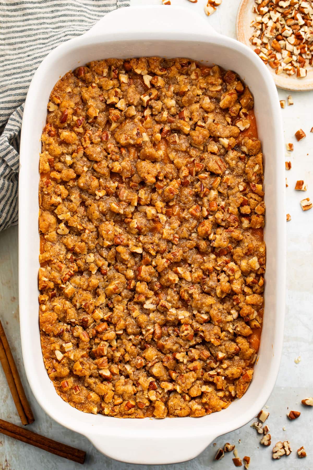 A casserole dish of Ruth's Chris sweet potato casserole topped with pecans and brown sugar.
