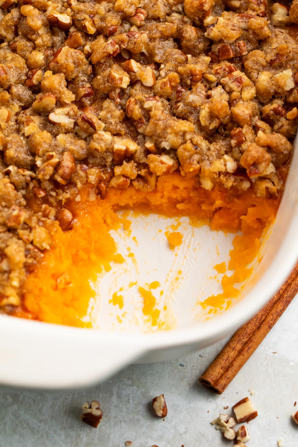 A casserole dish of Ruth's Chris sweet potato casserole topped with pecans and brown sugar, with a scoop of casserole missing from the corner of the dish.