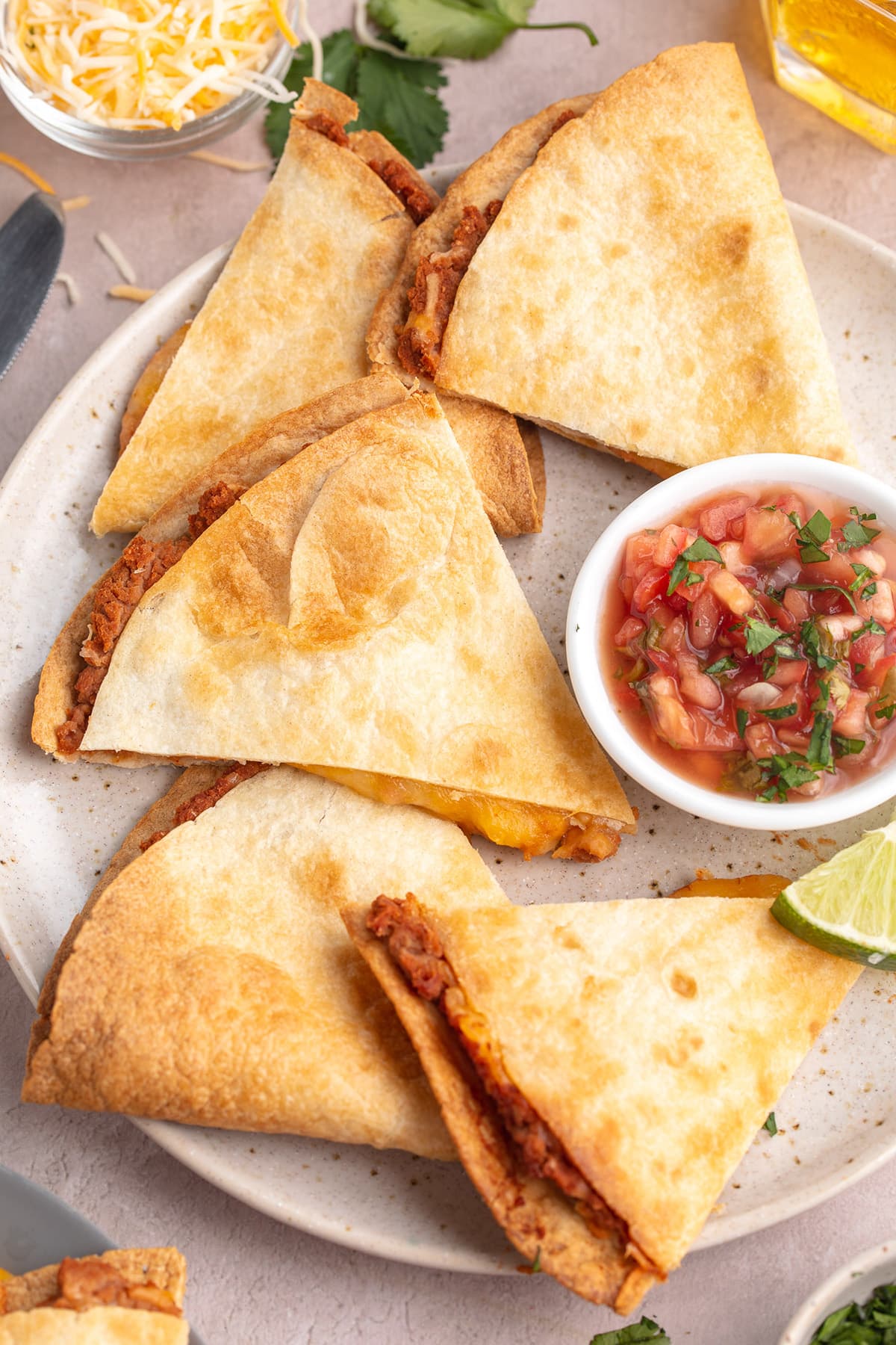 Triangular slices of air fryer quesadillas on a plate with a ramekin of salsa.