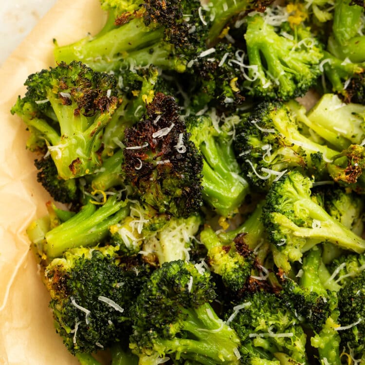 Air fryer frozen broccoli with crisp brown spots piled on parchment paper.