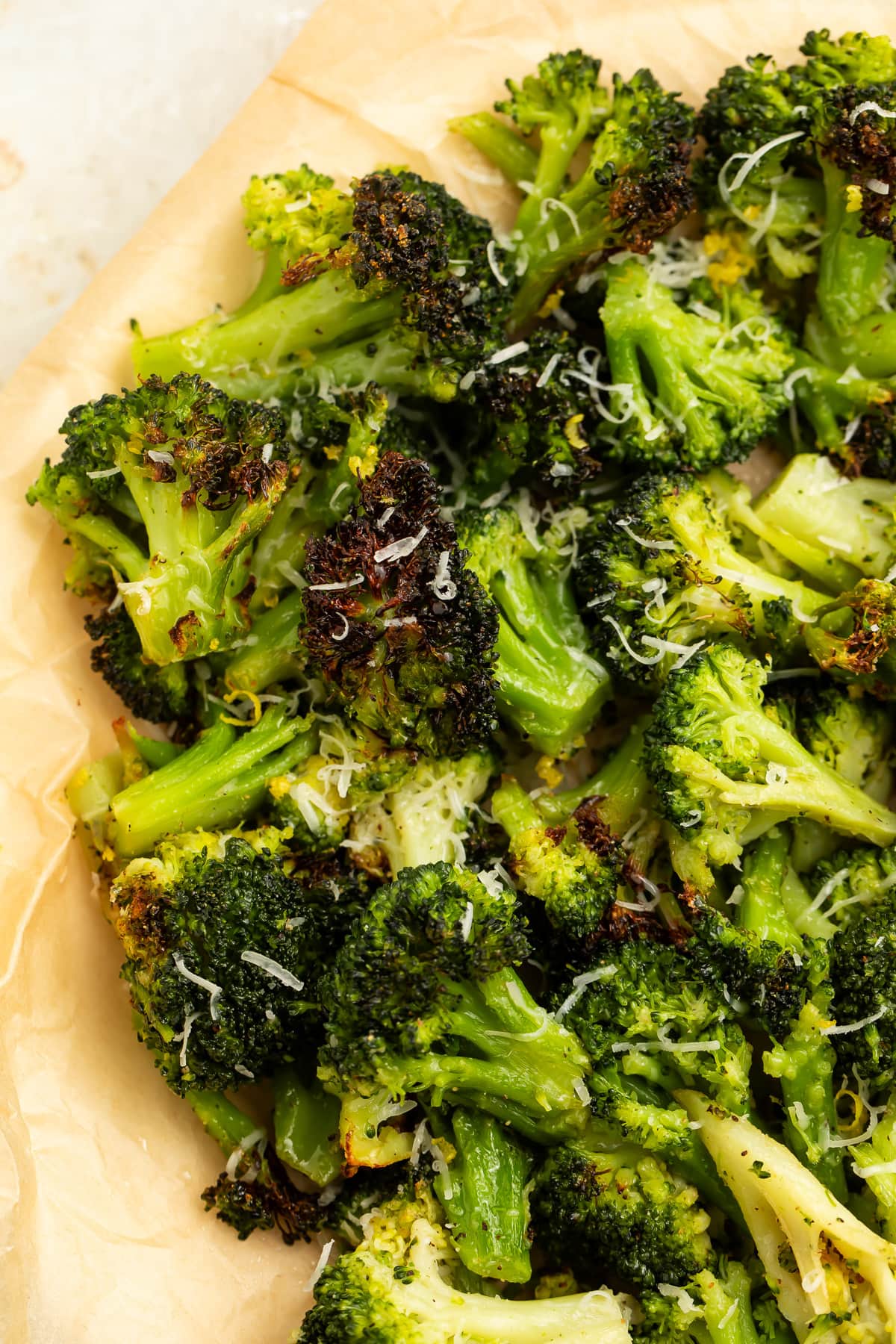 Air fryer frozen broccoli with crisp brown spots piled on parchment paper.