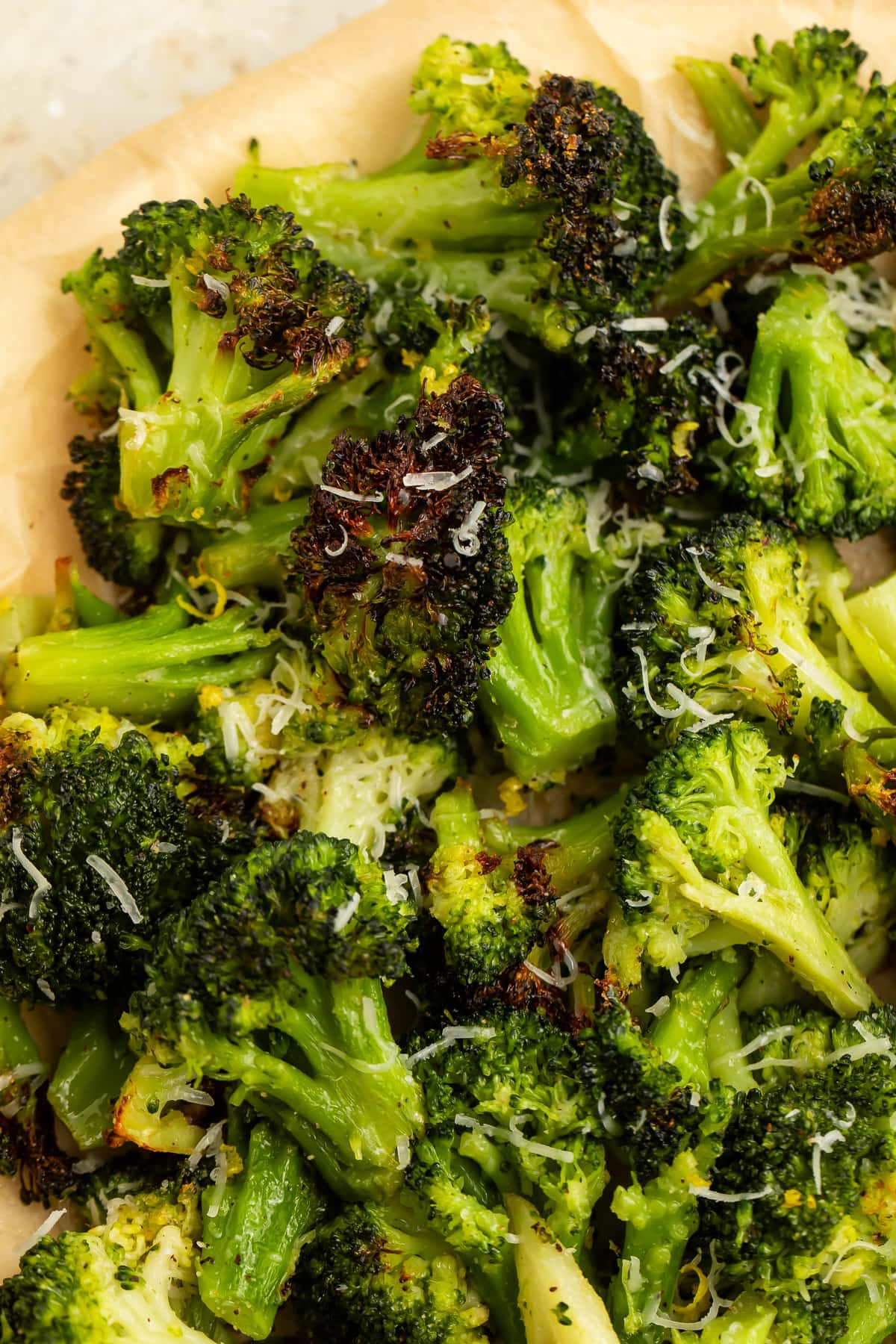 Air fryer frozen broccoli with crisp brown spots piled on parchment paper.