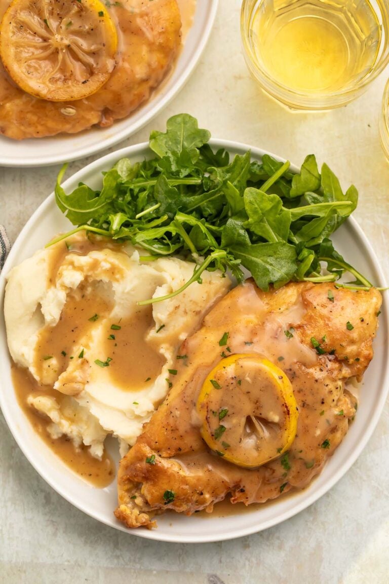 A plate of mashed potatoes and chicken francese with a small green leafy salad.