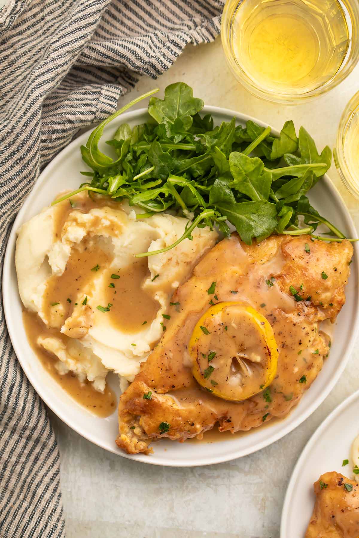 A plate of mashed potatoes and chicken francese with a small green leafy salad.