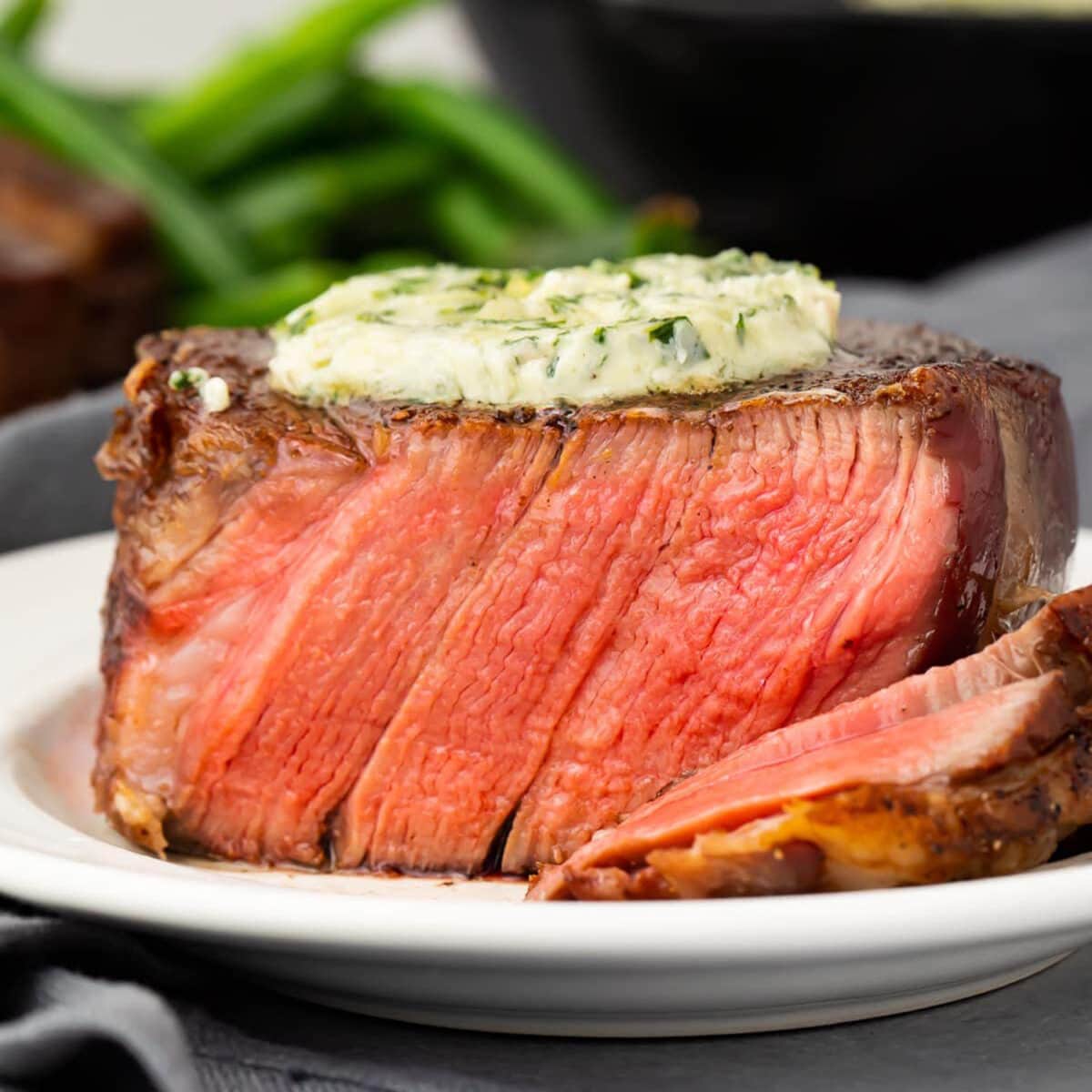 Medium-rare filet mignon, pink and juicy in the center, topped with a pat of garlic herb butter.