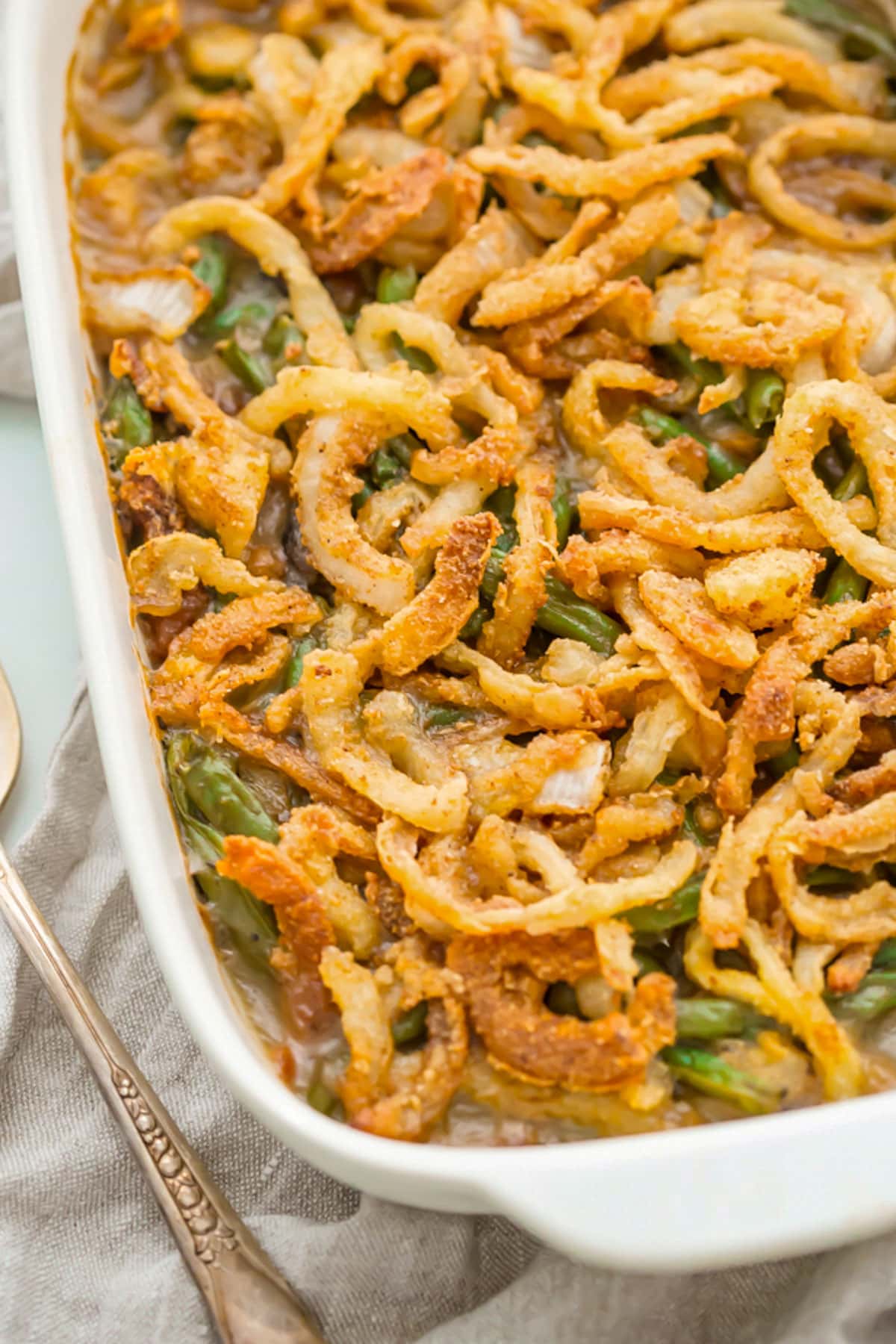 A large rectangular casserole dish holding a Whole30 green bean casserole topped with crispy onions.